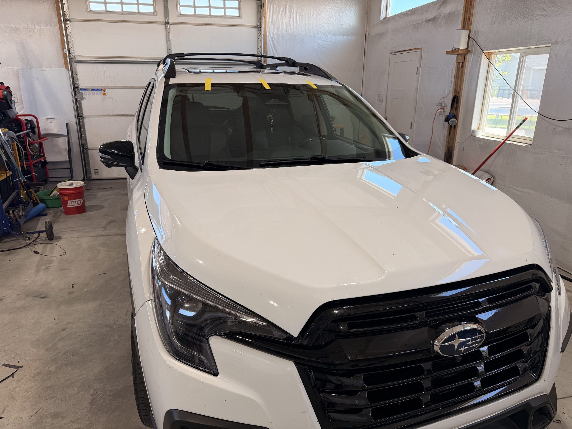 White Subaru SUV with a freshly set windshield secured with retention tape